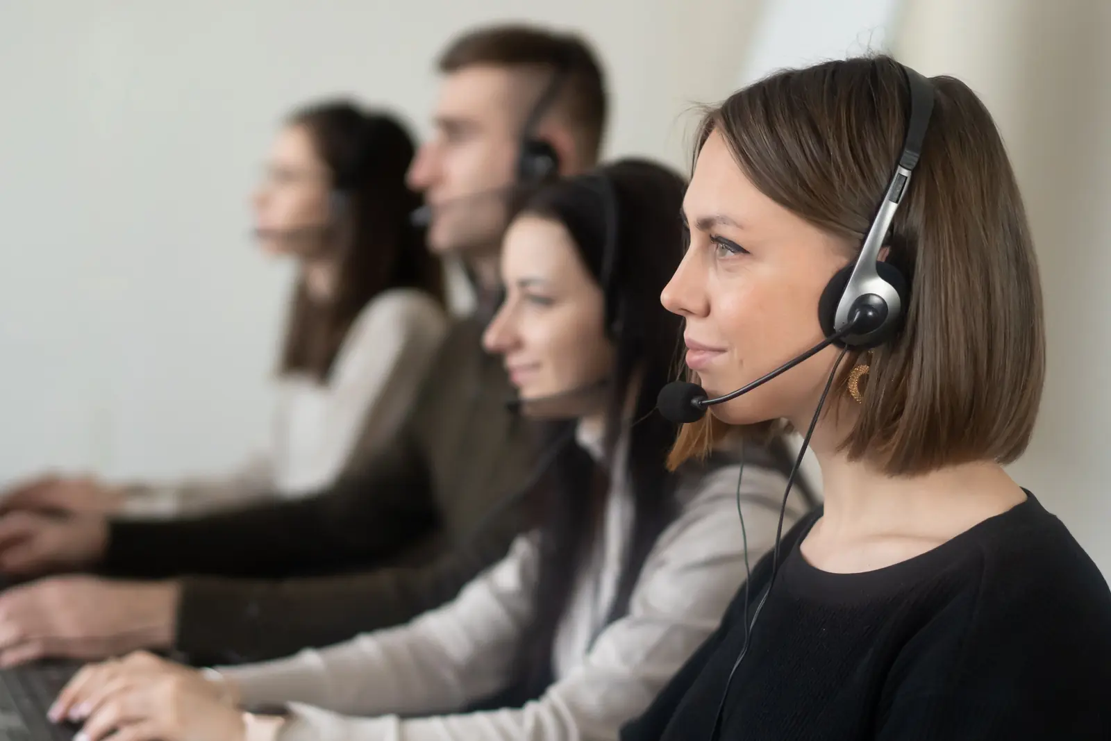 Betriebsmittelprüfung und Leiter- und Trittprüfung im Callcenter: Mitarbeitende mit Headsets an ihren Arbeitsplätzen.