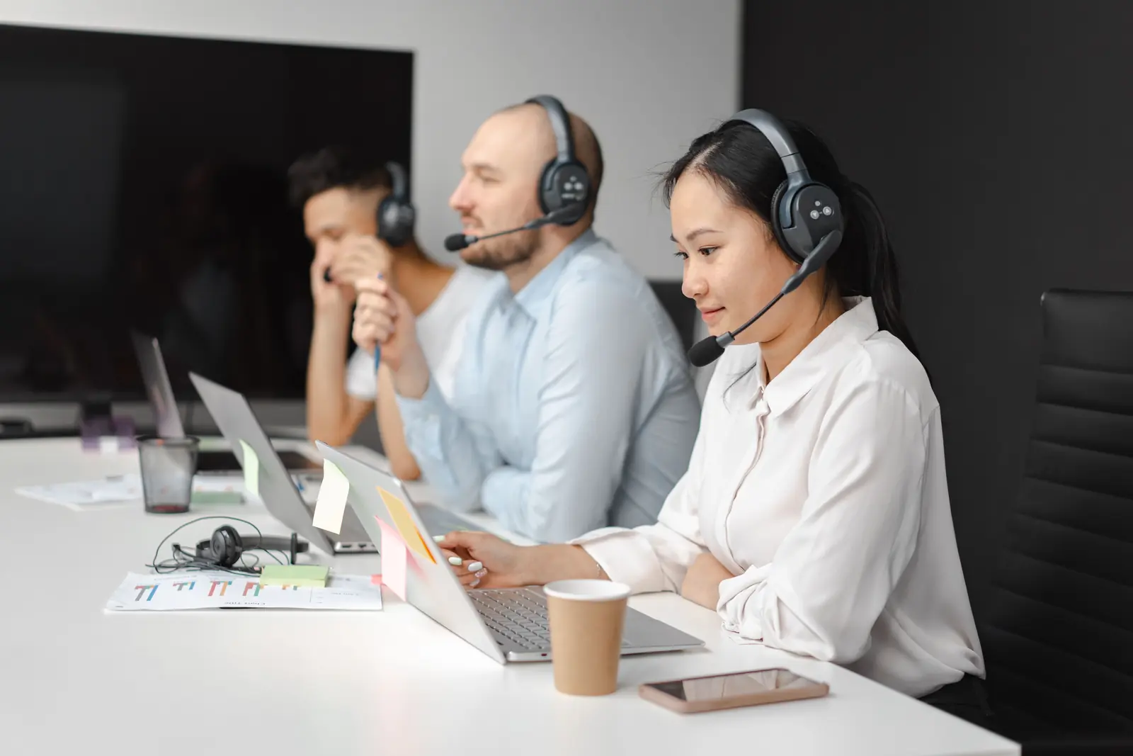 Betriebsmittelprüfung und Leiter- und Trittprüfung im Callcenter: Team mit Headsets und Notebooks im Besprechungsraum.