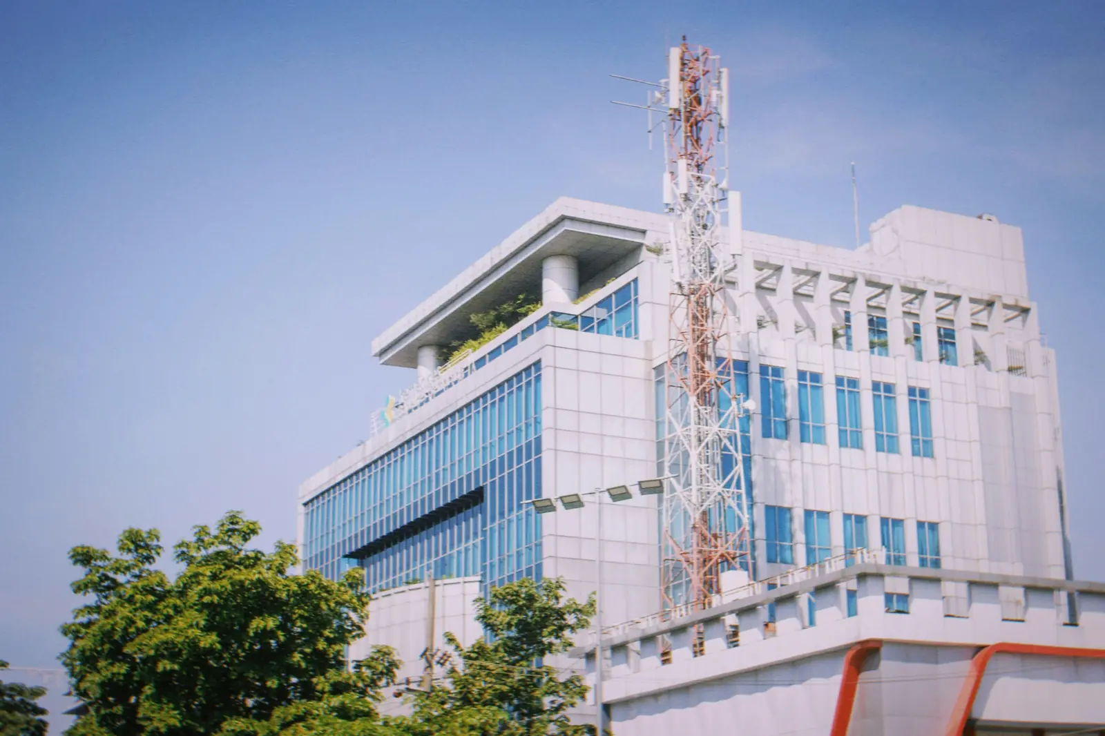 Betriebsmittelprüfung und Leiter- und Trittprüfung im Facility Management: Bürogebäude mit Antennenmast auf dem Dach.