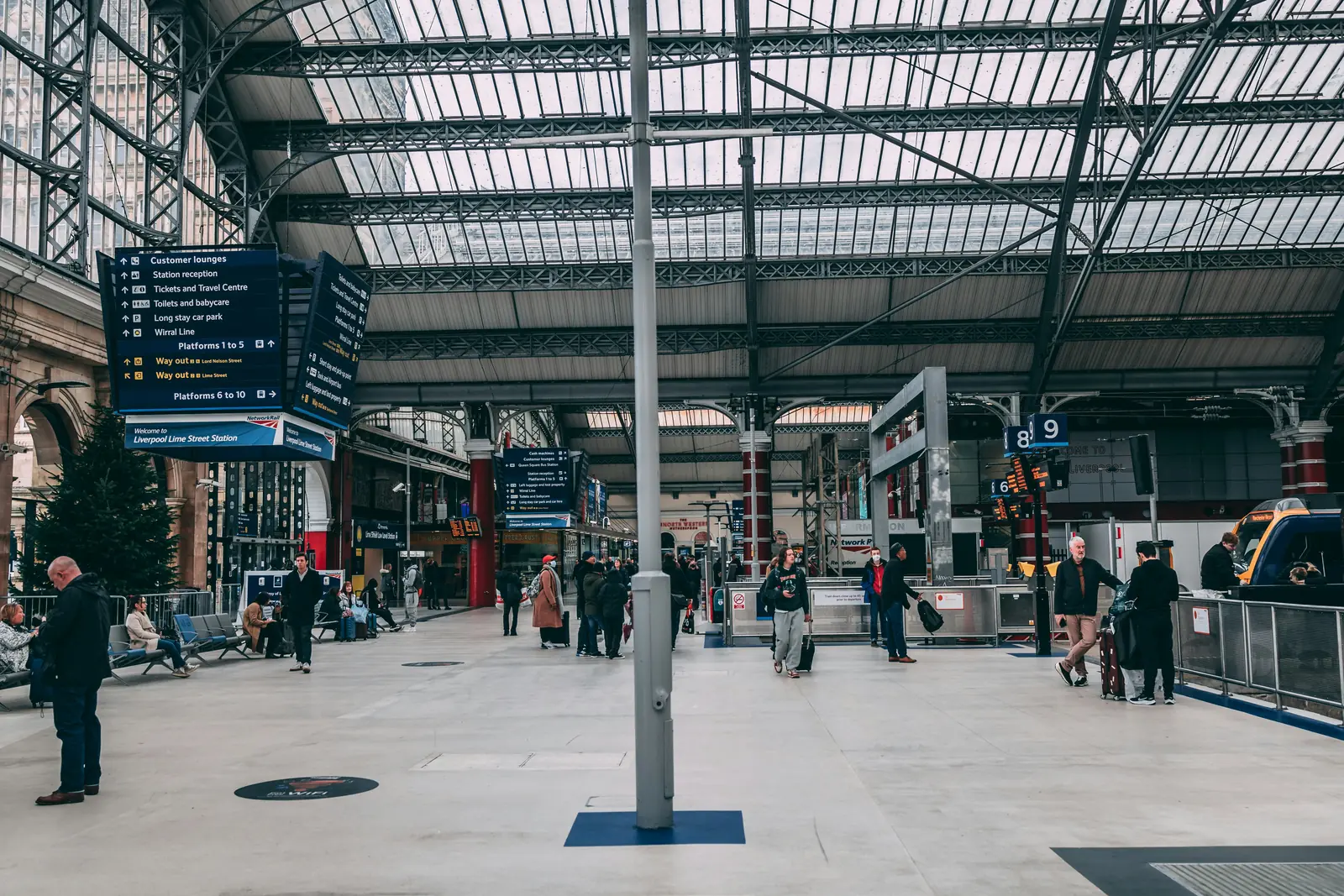 Betriebsmittelprüfung und Leiter- und Trittprüfung am Flughafen: Bahnsteighalle mit Glasdach und Anzeigetafeln.