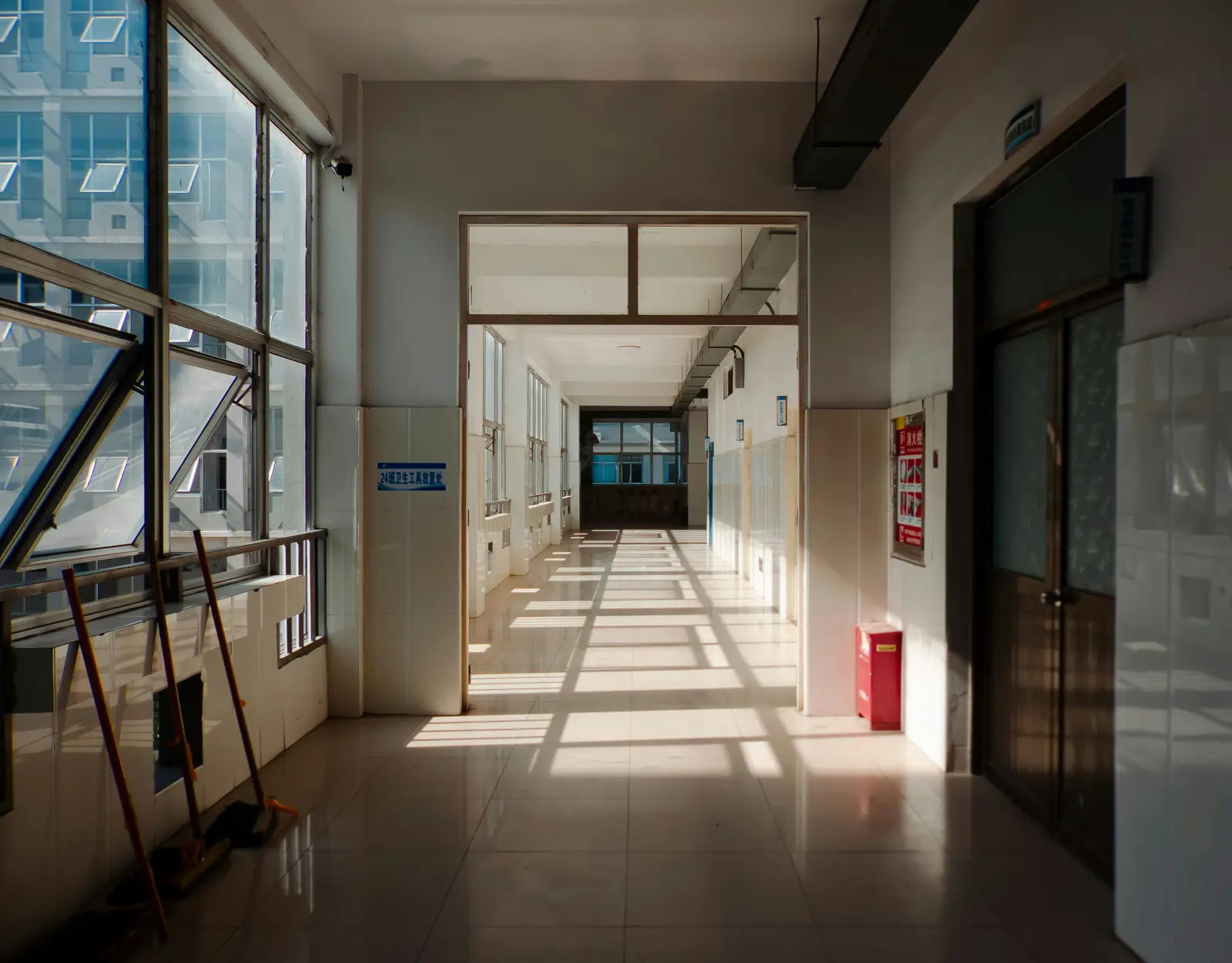 Betriebsmittelprüfung und Leiter- und Trittprüfung im Krankenhaus: Heller Flur mit Fensterfront und Reinigungsgerät.