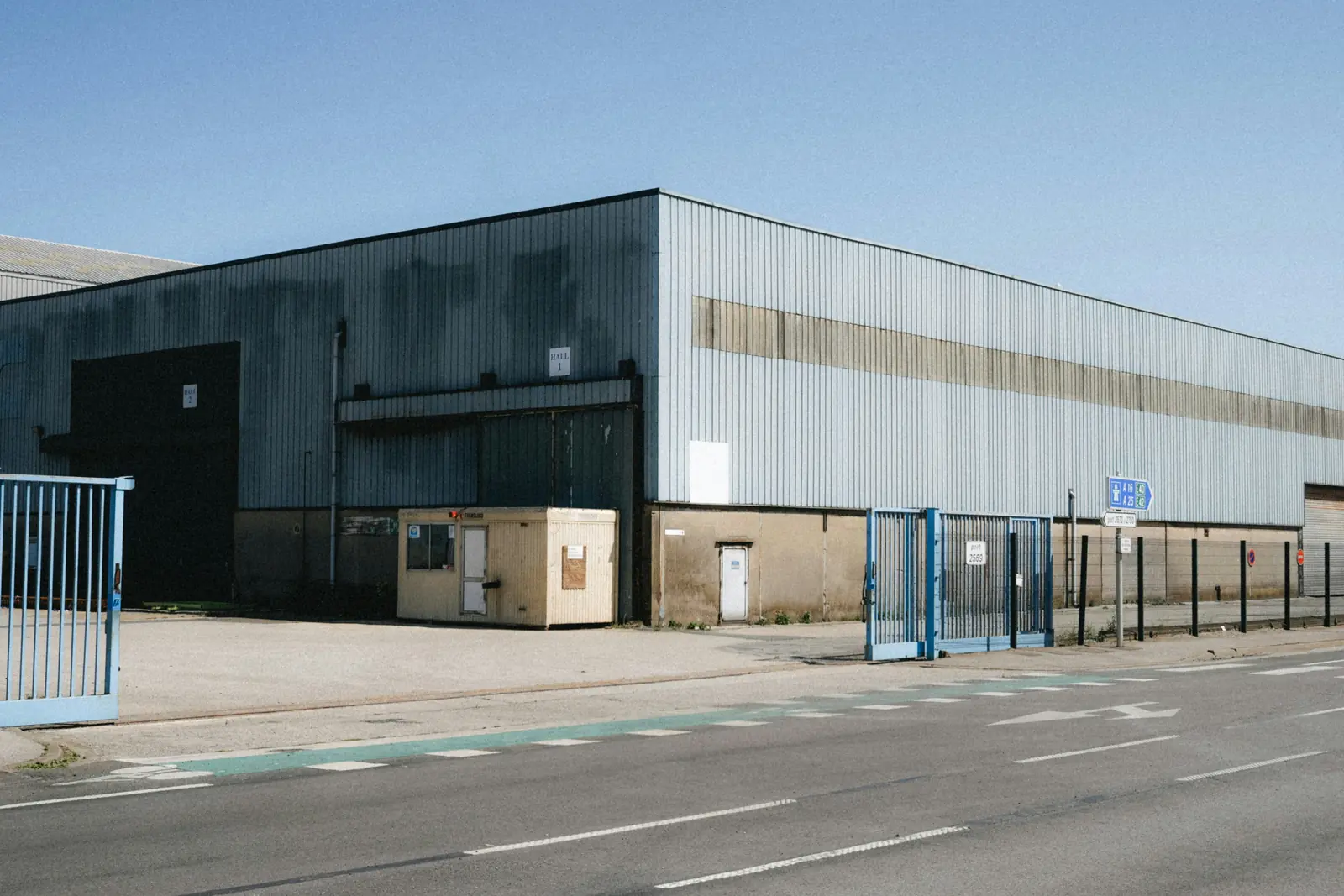 Betriebsmittelprüfung und Leiter- und Trittprüfung im Lager: Außenansicht einer Lagerhalle mit Toranlage.