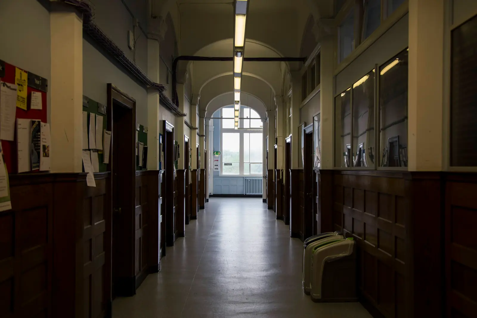 Betriebsmittelprüfung und Leiter- und Trittprüfung in der Schule: Langer Flur mit Deckenleuchten und Vitrinen.
