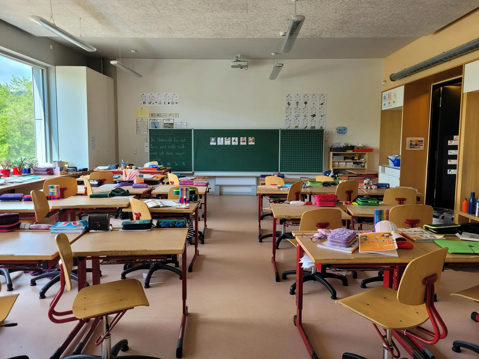 Betriebsmittelprüfung und Leiter- und Trittprüfung in der Schule: Klassenzimmer mit Tafel, Beamer und Pulten.