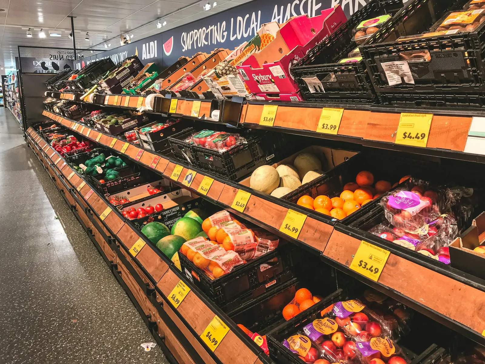 Betriebsmittelprüfung und Leiter- und Trittprüfung im Supermarkt: Obst- und Gemüseabteilung mit Deckenbeleuchtung.