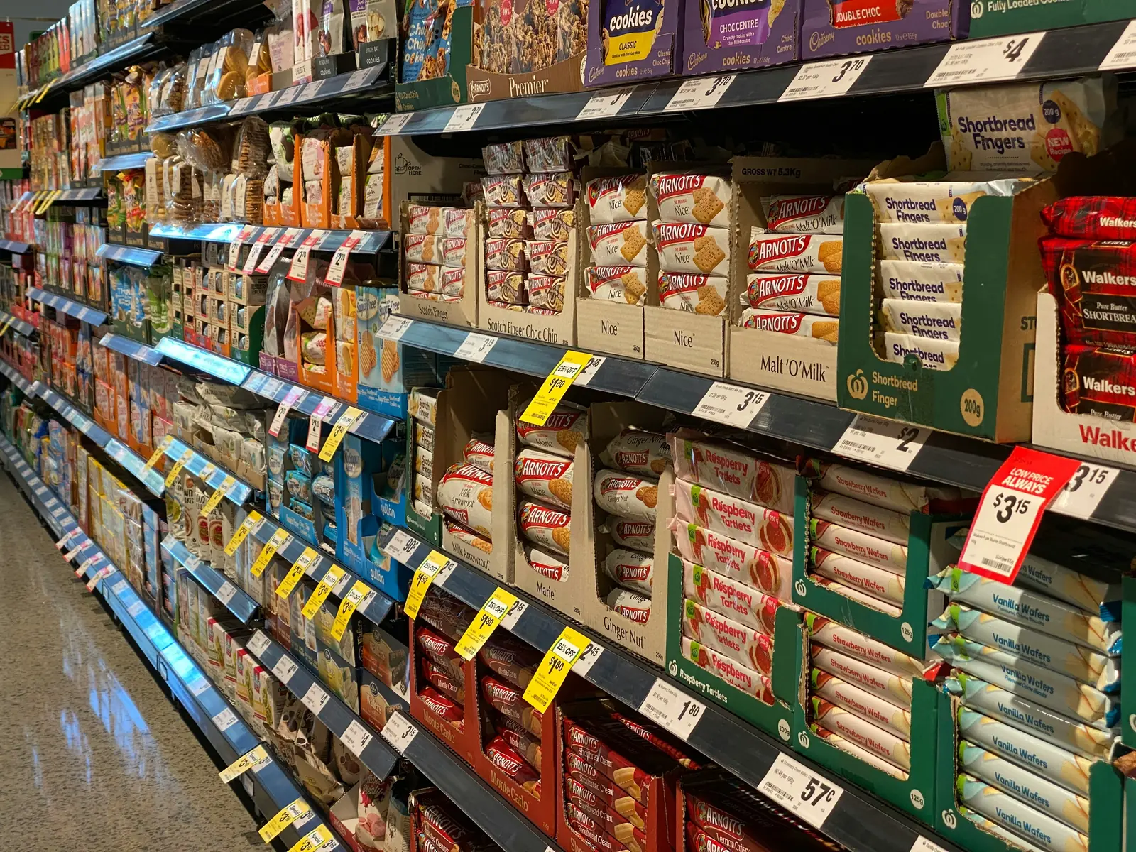 Betriebsmittelprüfung und Leiter- und Trittprüfung im Supermarkt: Vollgeräumte Regalreihe mit Preisschildern.