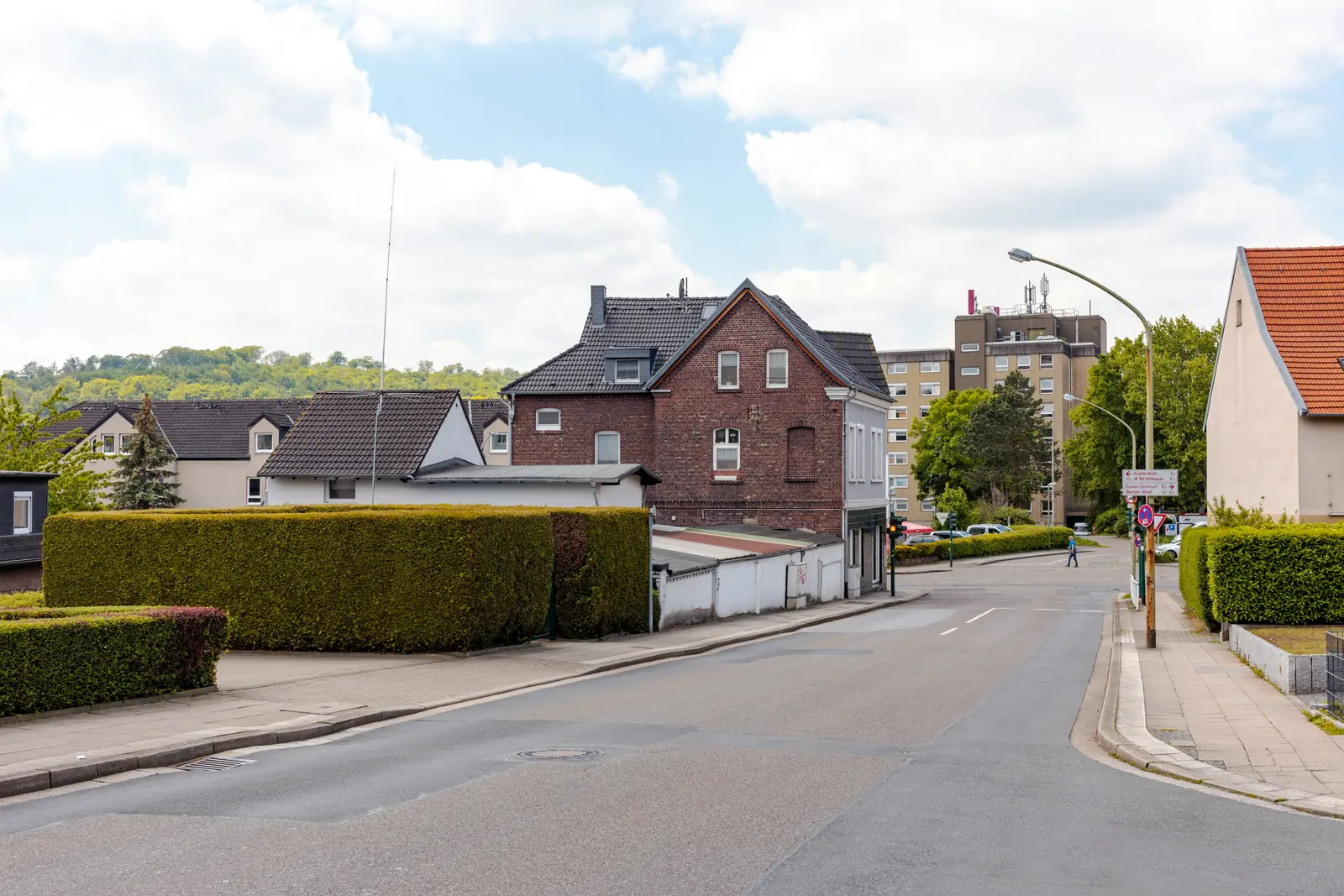 Betriebsmittelprüfung und Leiter- und Trittprüfung im Ruhrgebiet: Wohnstraße mit Backsteinhaus und Hochhaus.