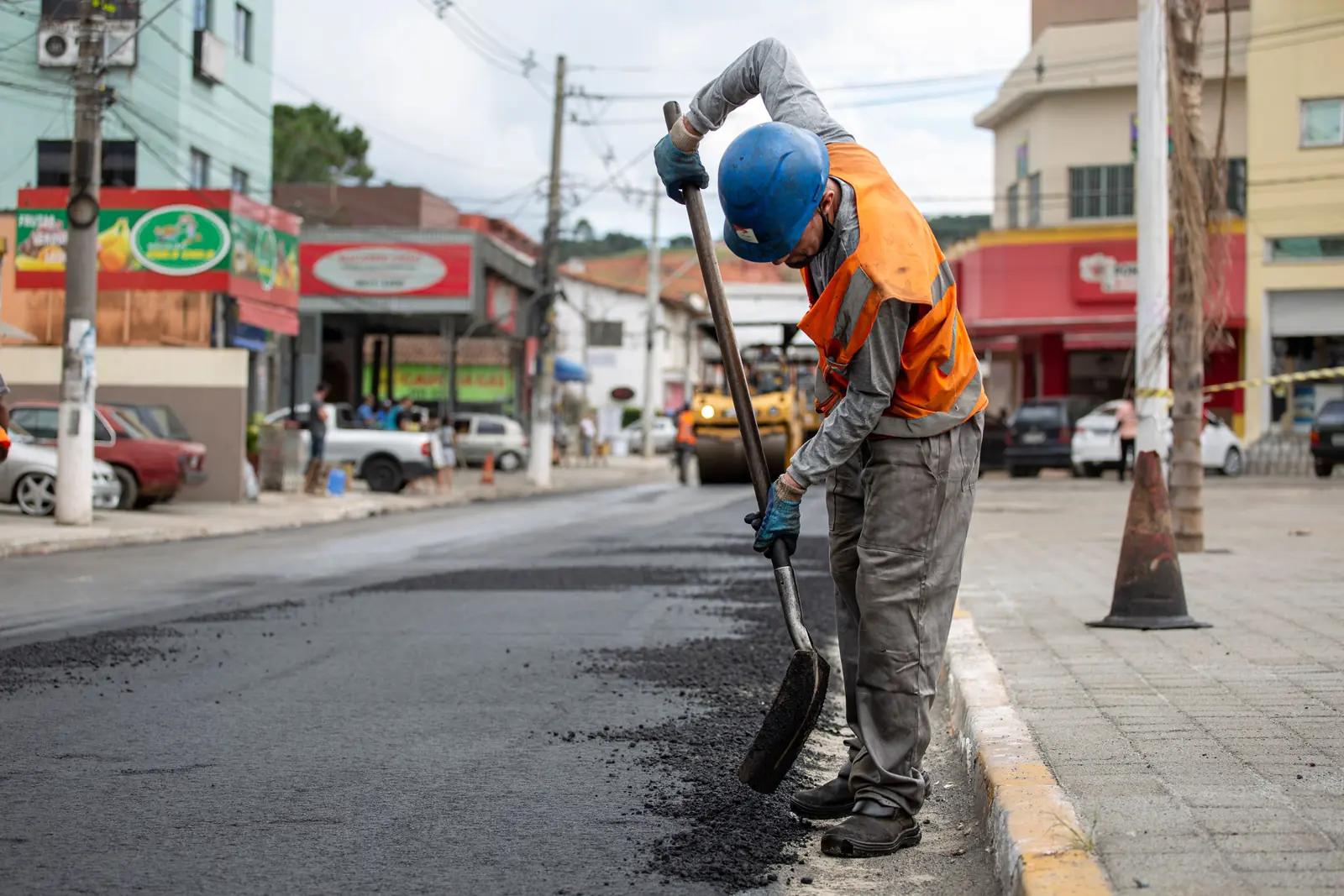 Betriebsmittelprüfung und Leiter- und Trittprüfung bei den Stadtwerken: Straßenbauer verteilt Asphalt mit der Schaufel.