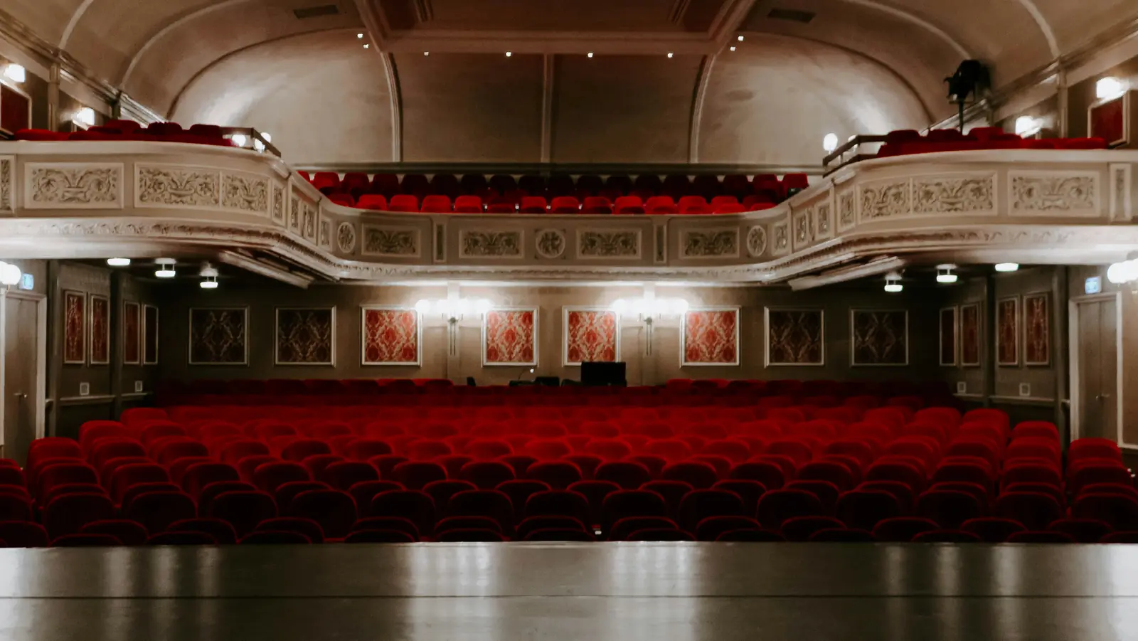 Betriebsmittelprüfung und Leiter- und Trittprüfung im Theater: Historischer Saal mit Rängen und roten Sitzreihen.
