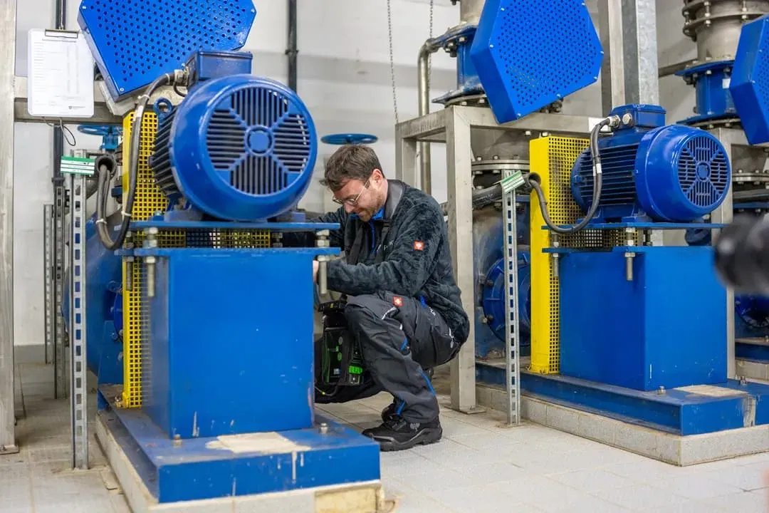 Ein Mann arbeitet in einer Fabrik an einer blauen Maschine.