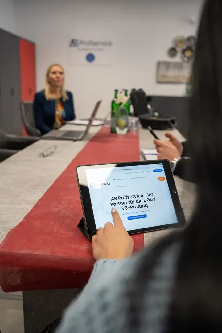 Eine Gruppe von Menschen sitzt an einem Tisch mit einem iPad vor sich.