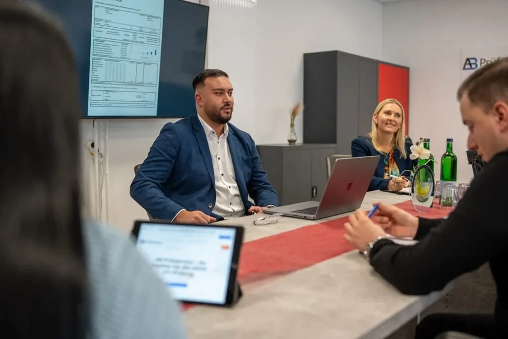 Eine Gruppe von Menschen sitzt um einen Tisch in einem Konferenzraum.