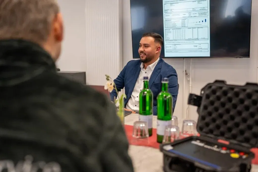 Zwei Männer sitzen an einem Tisch und reden miteinander.