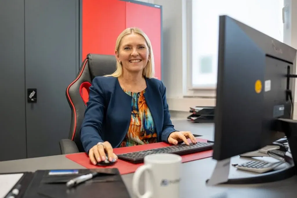 Eine Frau sitzt an einem Schreibtisch vor einem Computer.